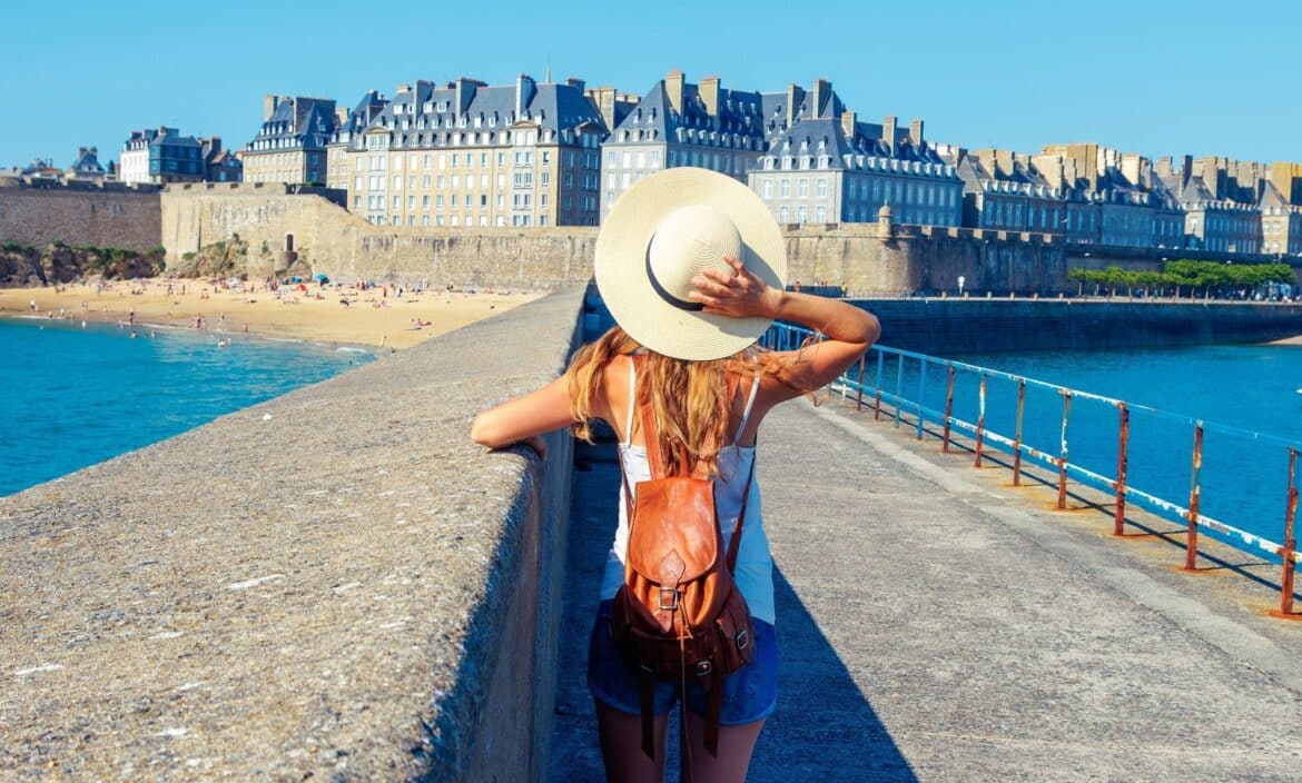Jeune femme de dos caché sous son chapeau d'été qui admire intra-muros